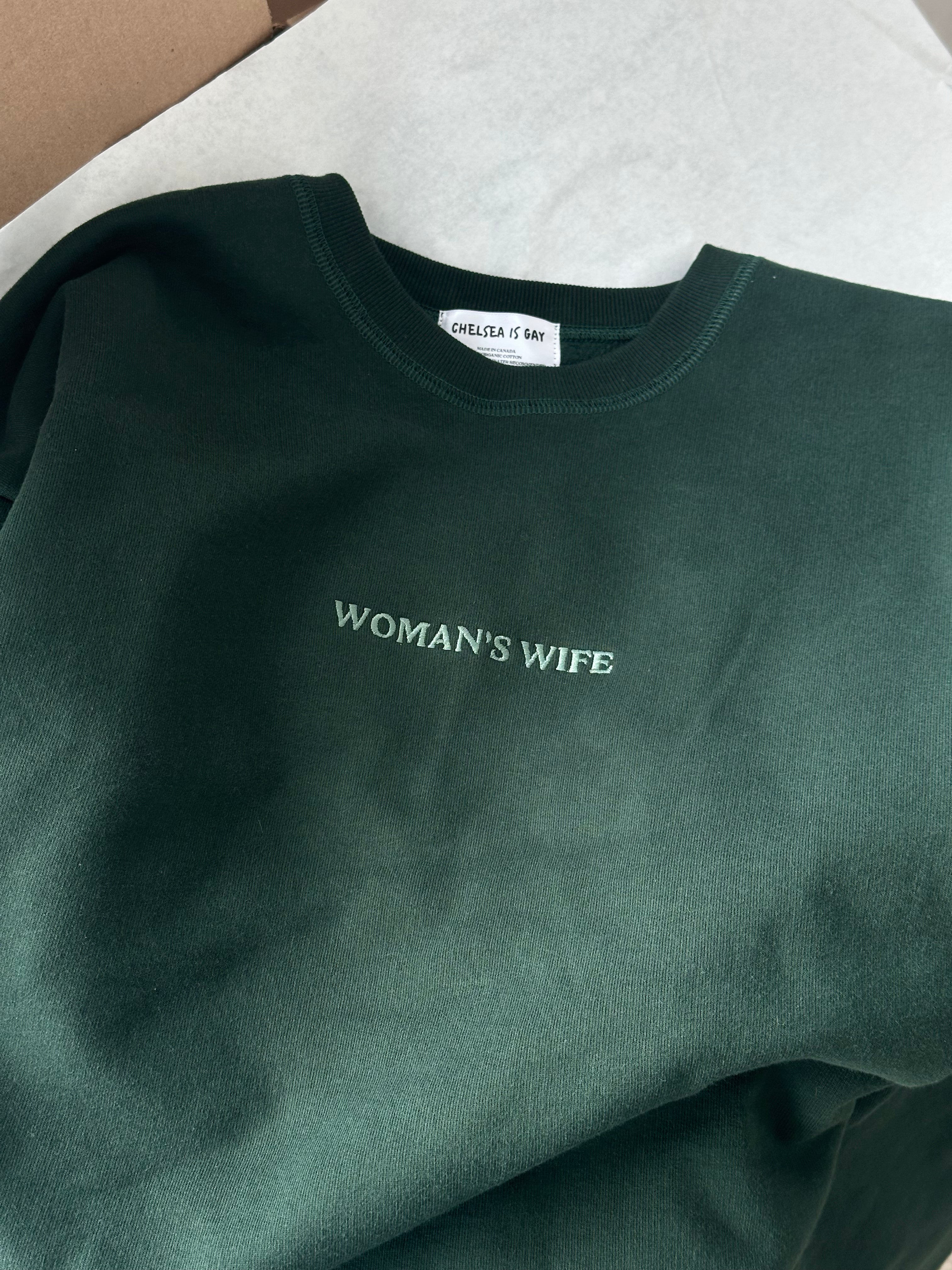 Dark green sweatshirt with 'WOMAN'S WIFE' text on a white background with brand label 'Chelsea is Gay'