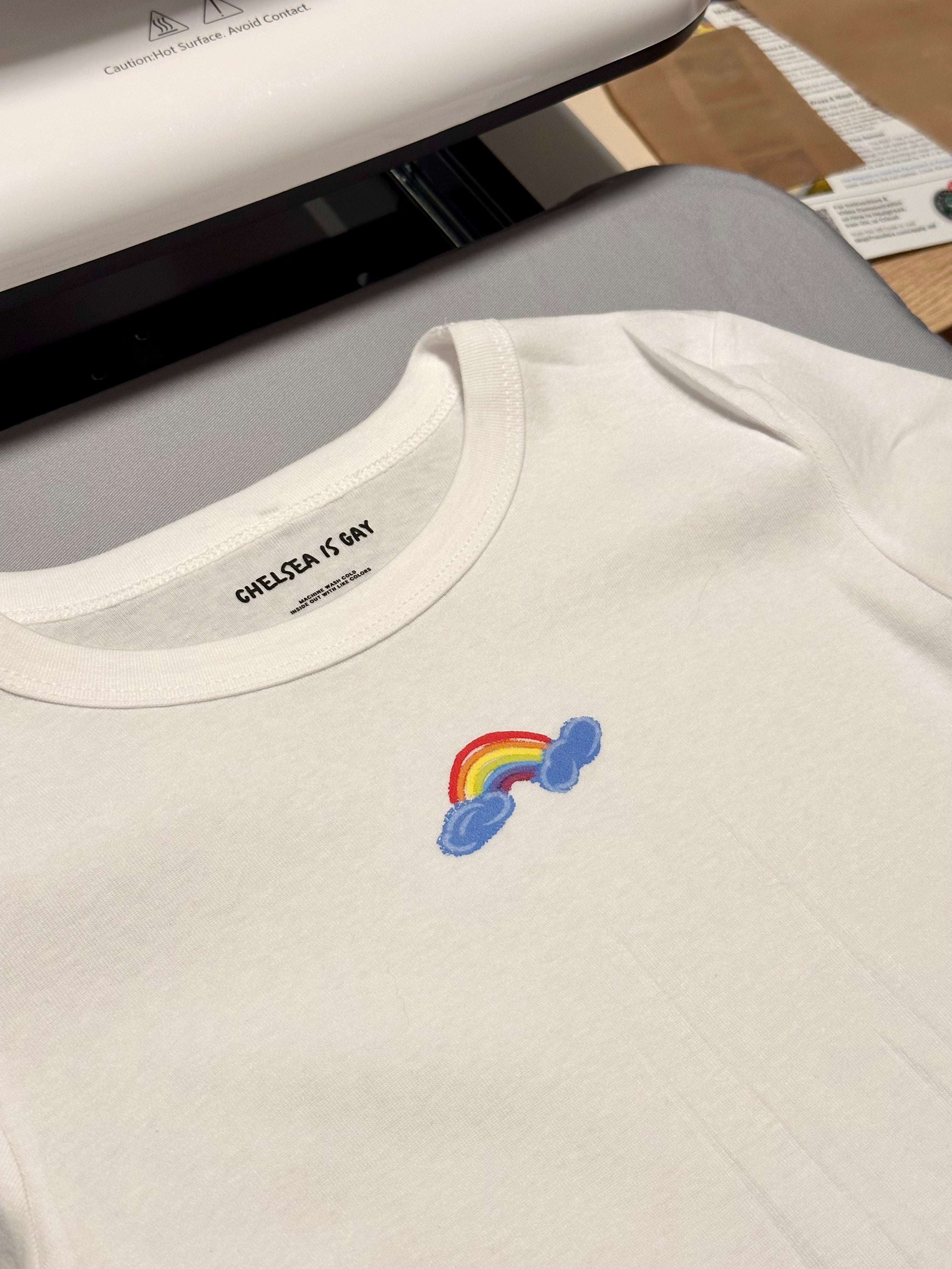 White pride t-shirt with minimal rainbow and cloud design 