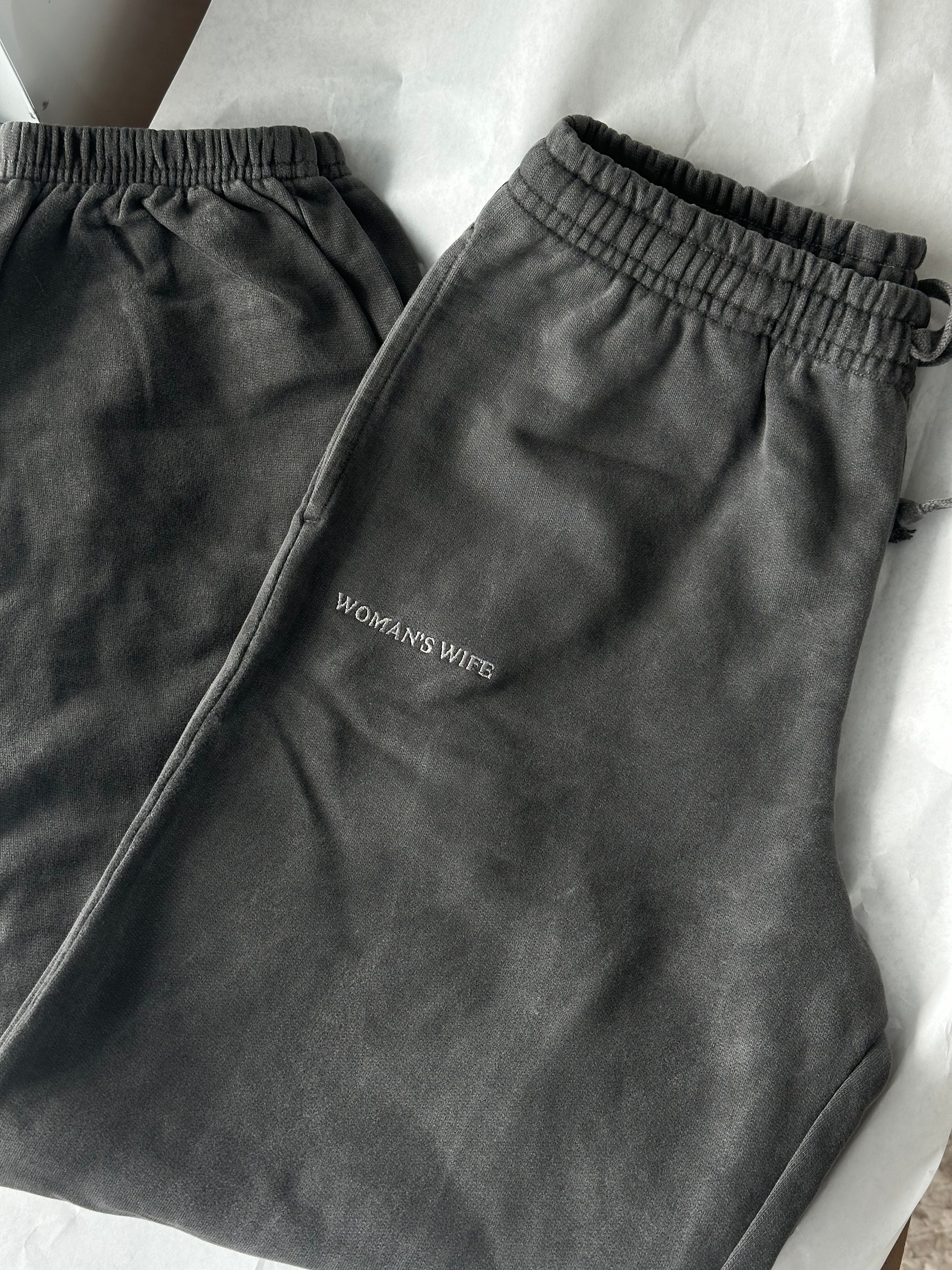 grey drawstring sweatpants with 'WOMAN'S WIFE' embroidered below the right pocket