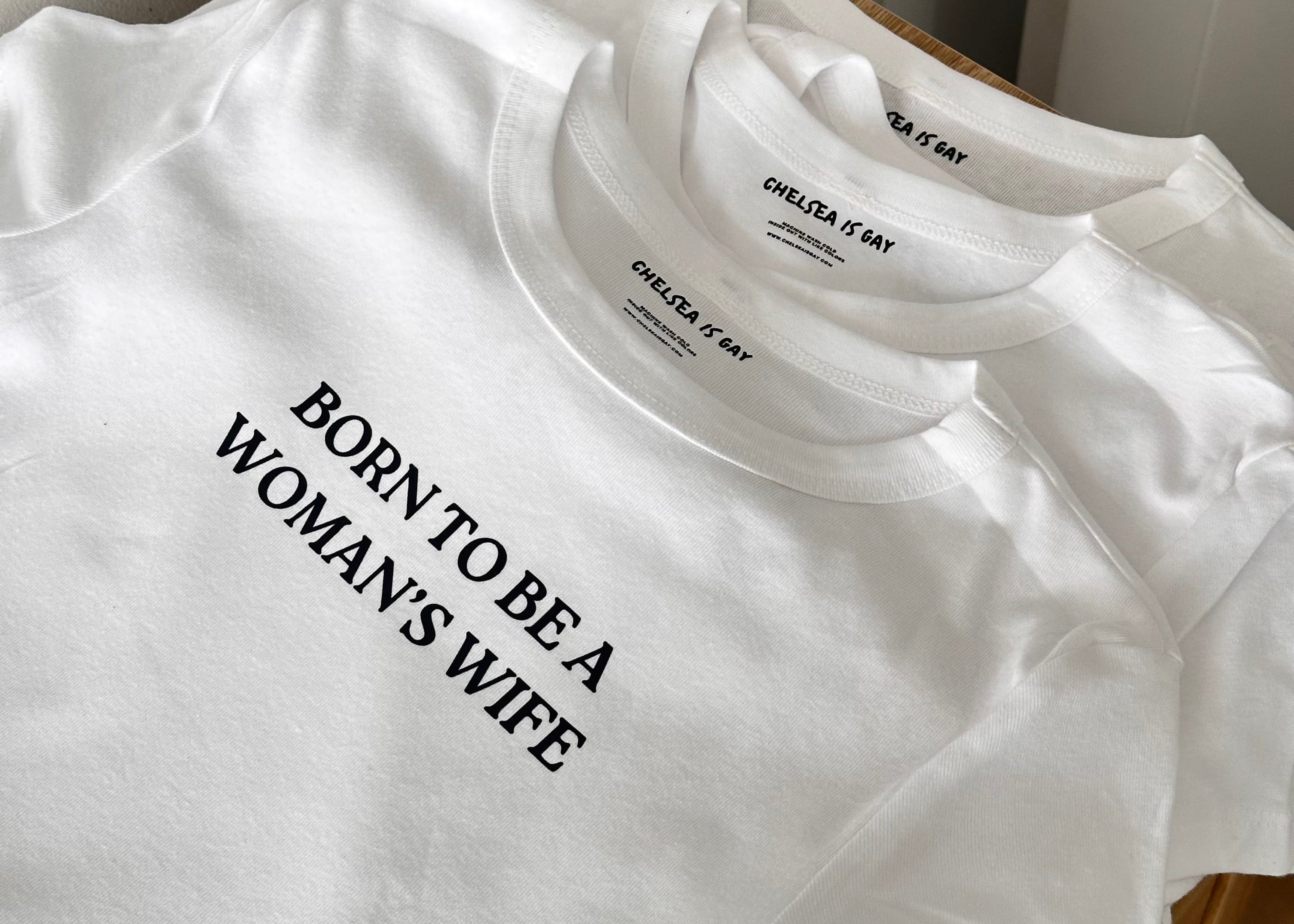 White t-shirt with text 'BORN TO BE A WOMAN'S WIFE' 