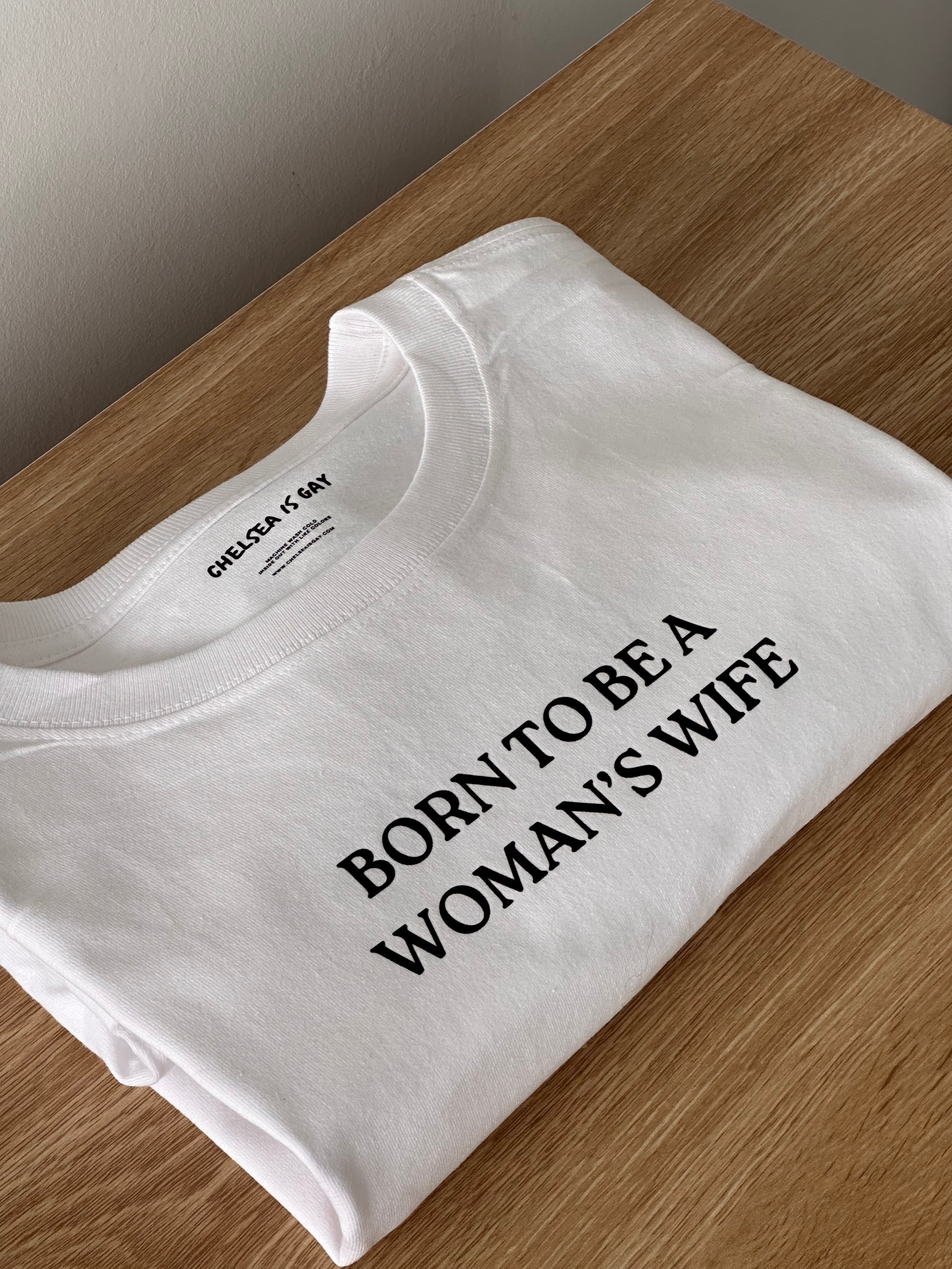 white folded tshirt with 'born to be a woman's wife' text on a wooden surface